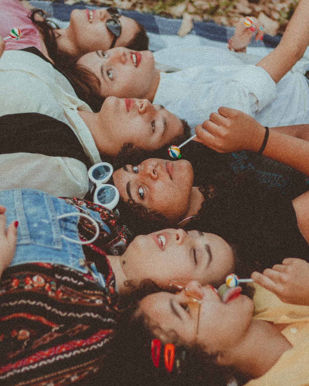 group of woman lying on blanket eating lollipops